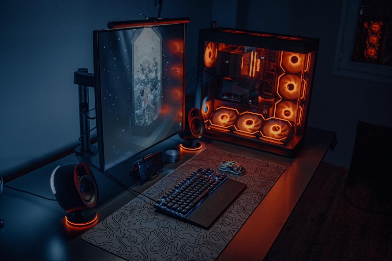 PC Desktop Personalizzati: Molto più di un semplice computer Sleek gaming desk setup featuring RGB lighting, large monitor, and gaming PC with glowing fans.